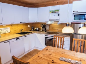 Eine kleine Küche mit weißen Schränken, einer Holz Arbeitsplatte, einem Einbauofen und einer Mikrowelle.