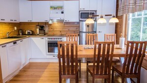 A modern kitchen with white cabinets, a wooden dining table, and four wooden chairs.