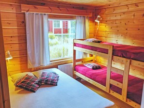 Ein Schlafraum mit Etagenbett, Fenster, Heizkörper und einer Nachttischlampe.