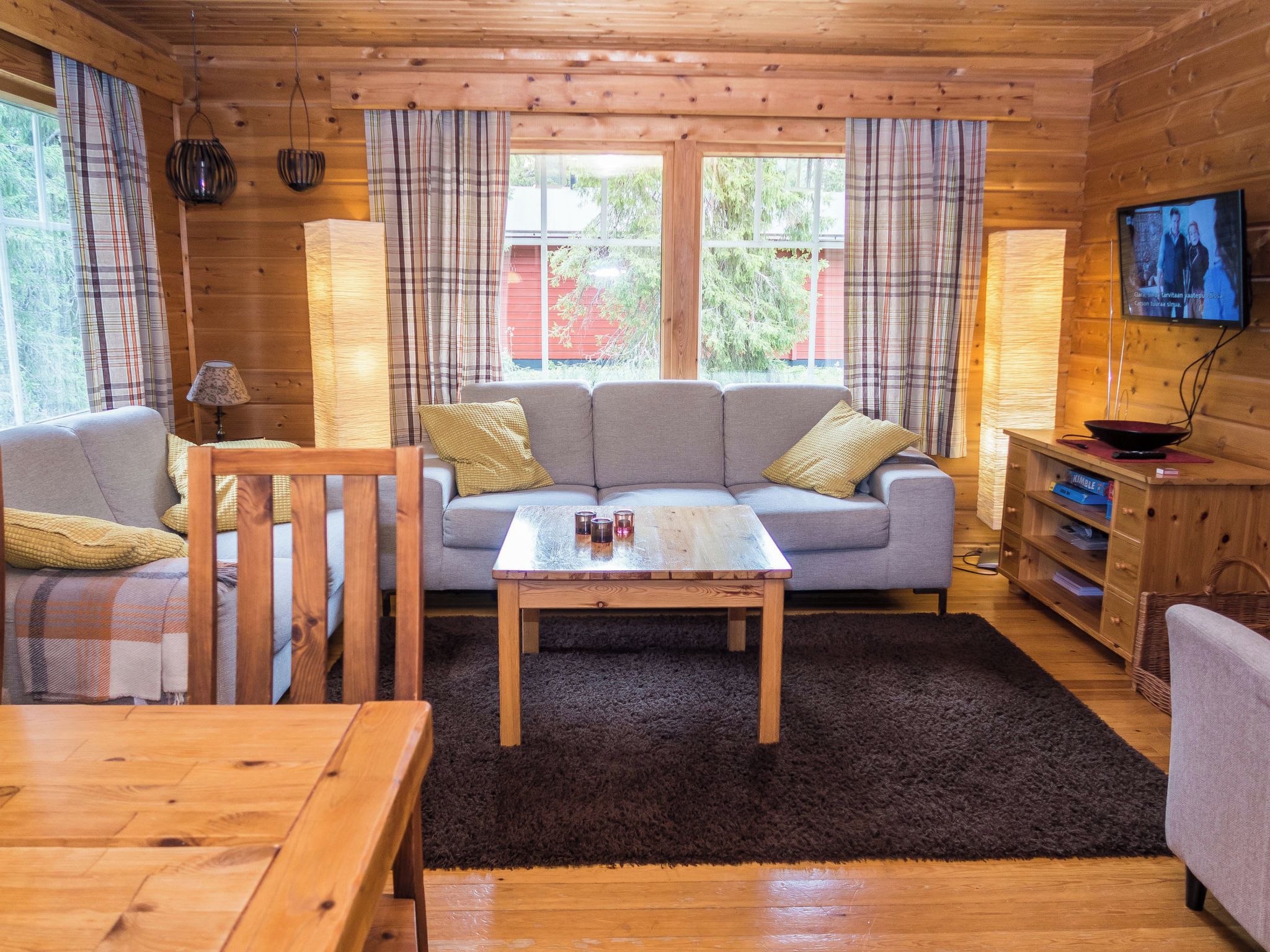 L’intérieur d’un chalet accueillant, avec un canapé, une table en bois et un téléviseur.