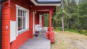 A red wooden building with a covered porch and a small white table.