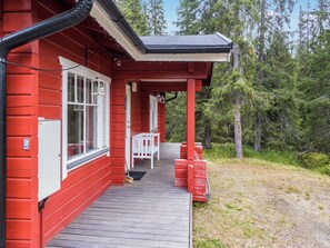 Una casa de madera roja con un porche cubierto y una terraza de madera.