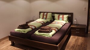 A double bed with a wooden frame, two bedside tables, and a nightstand with a lamp. - Mier Gfallt's by Interhome (Saas-Fee)