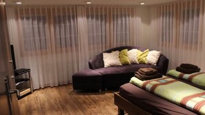 A bedroom with a sofa bed, a single bed, and a wooden floor. - Mier Gfallt's by Interhome (Saas-Fee)