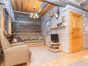A log cabin interior with a sofa, armchair, television, and a wall-mounted radio. - Pajalan honka by Interhome (Kuusamo)