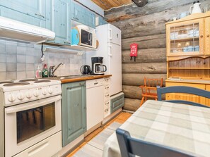 Une cuisine compacte équipée d’une cuisinière, d’un four à micro-ondes et d’un évier. On y trouve un meuble en bois avec des portes en verre, ainsi qu’une petite table avec des chaises.