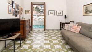 Ein Wohnzimmer mit Fernseher, Sofa und Blick auf eine Küstenstadt durch eine Glastür.