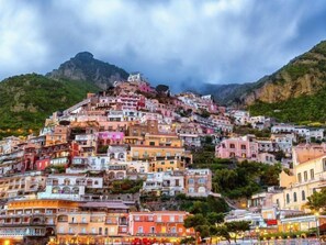 Un pueblo en una ladera densamente poblada, con edificios coloridos, terreno escarpado y montañas al fondo.