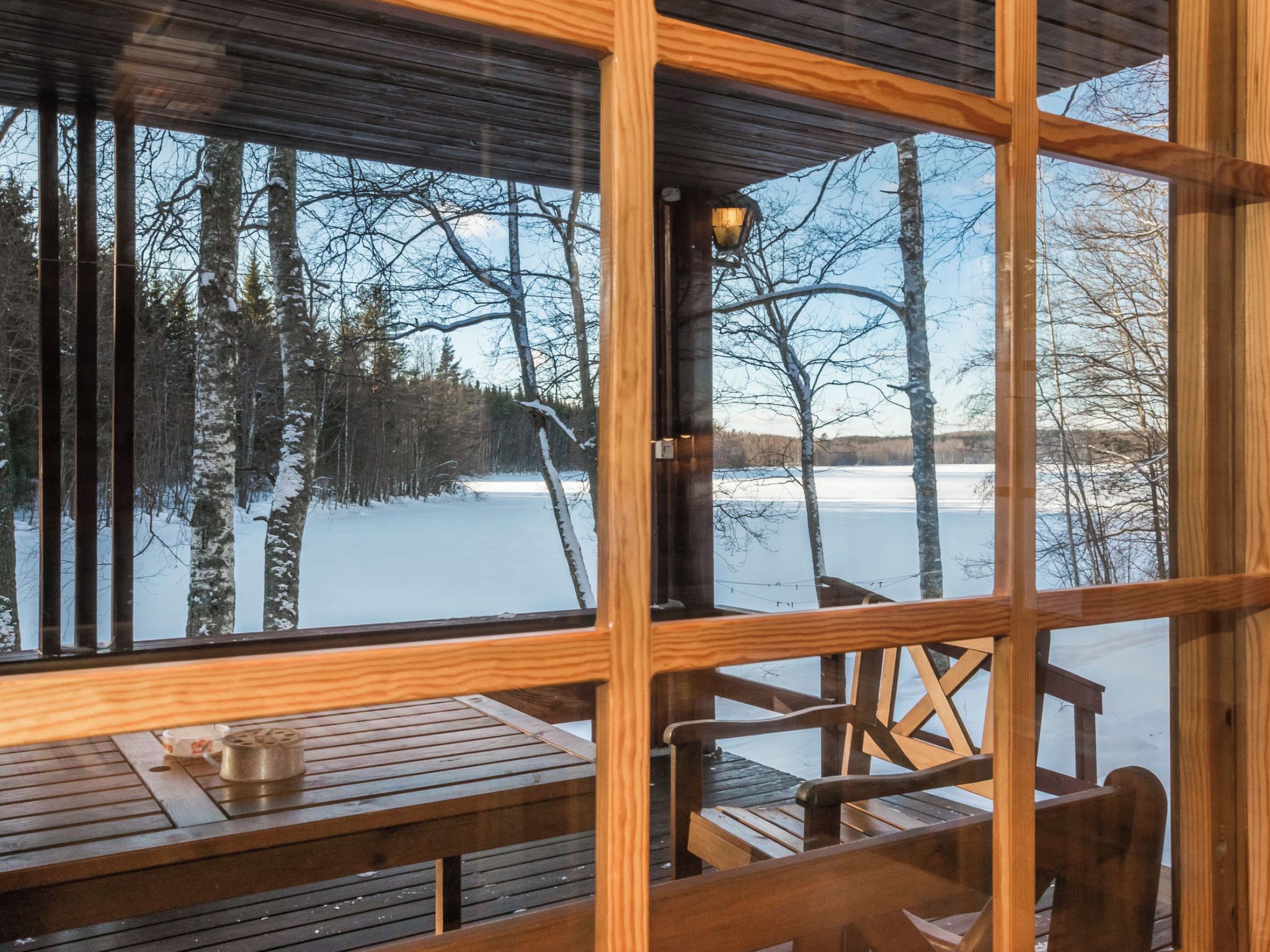 A wooden cabin with a large window overlooking a snowy landscape.
