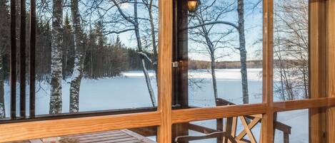 A wooden cabin with a large window overlooking a snowy landscape.