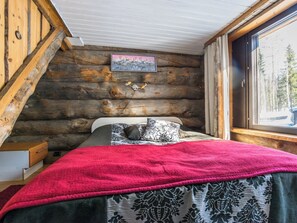 Un dormitorio tipo cabaña de madera con una cama, un ventanal y un cuadro en la pared.