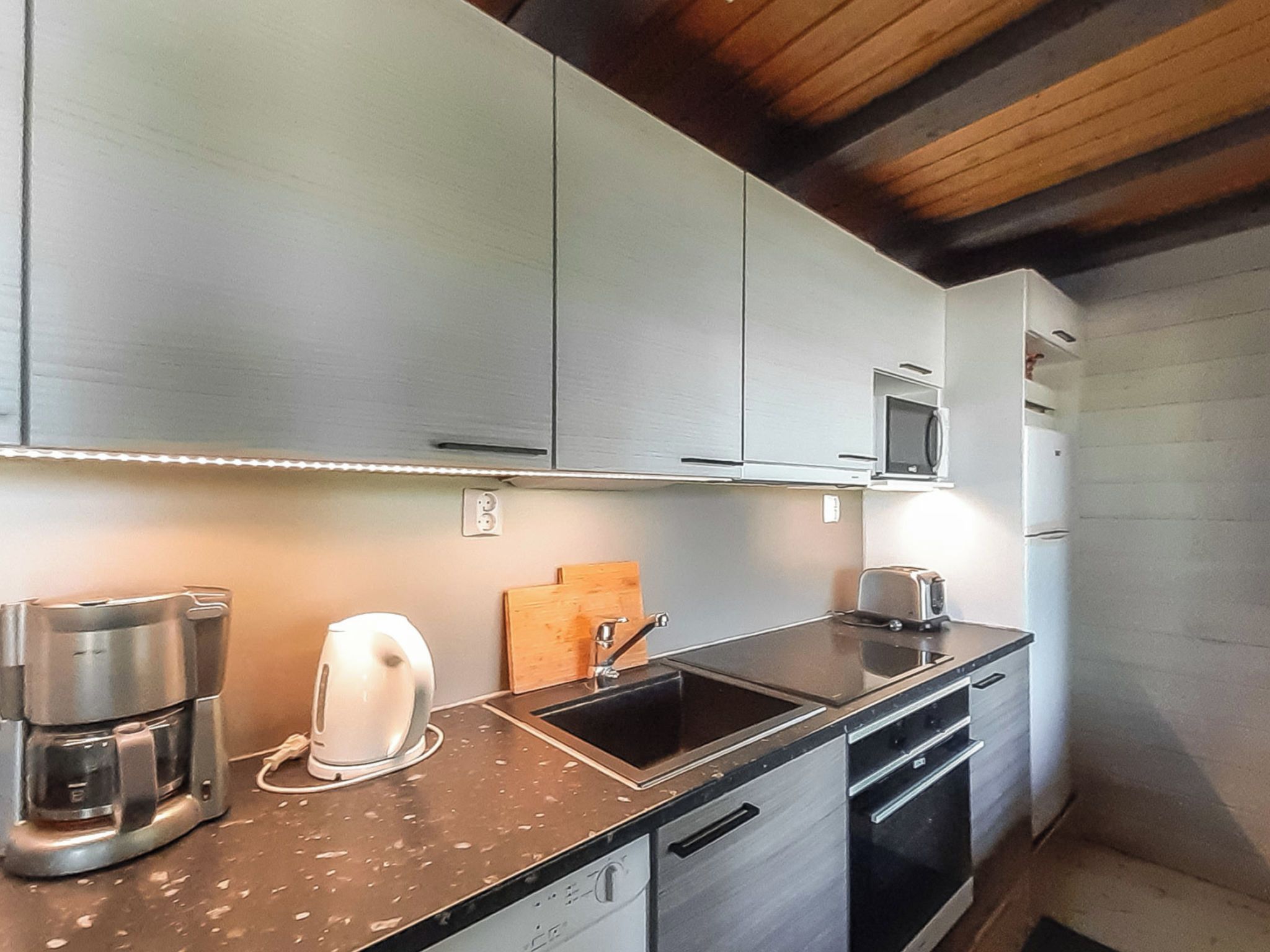 A modern kitchen with stainless steel appliances, a built-in microwave, and a coffee maker.
