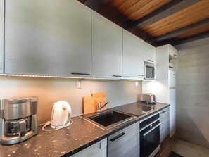 Una cocina moderna con electrodomésticos de acero inoxidable, un microondas integrado y una cafetera.