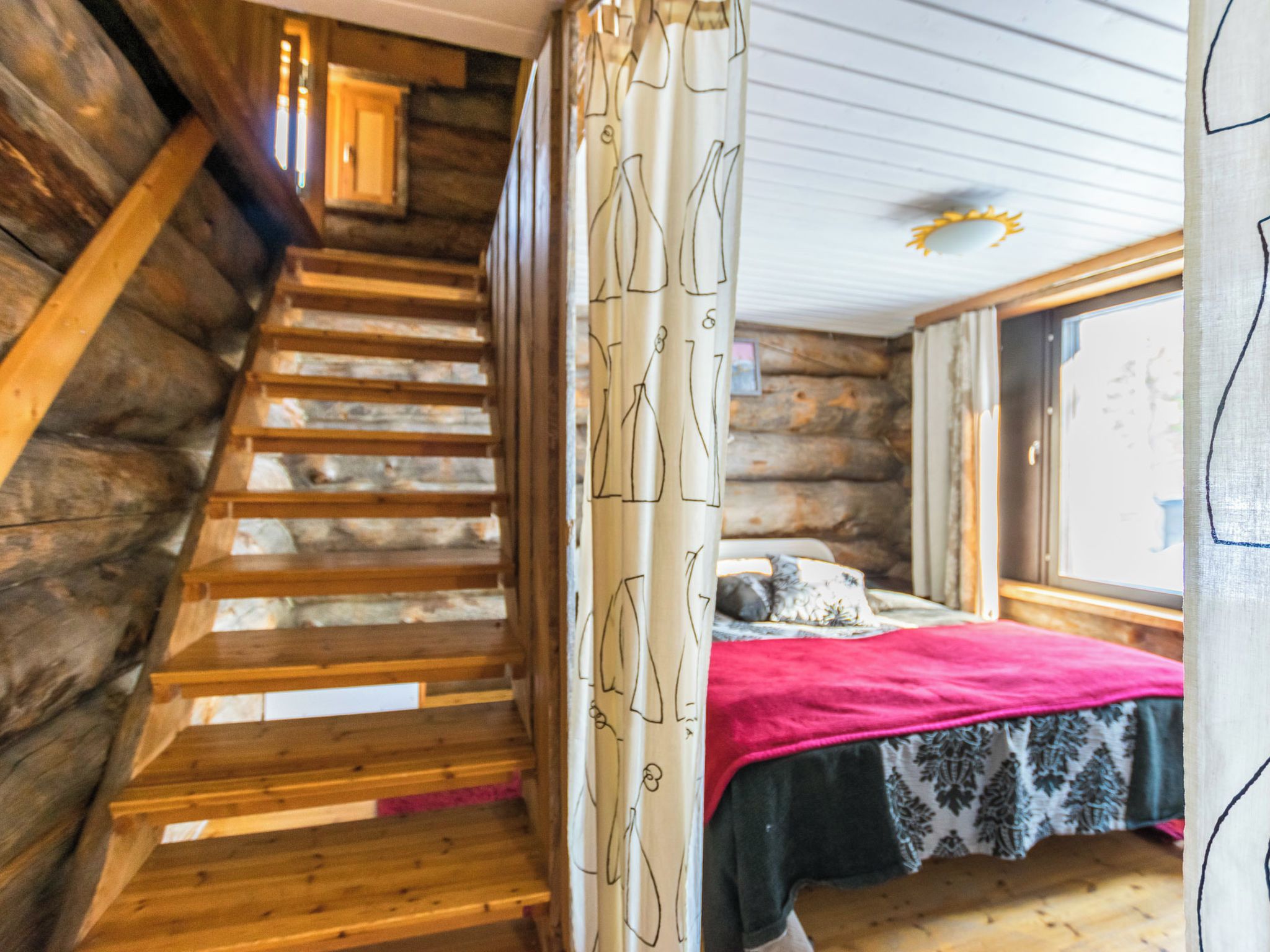 A wooden staircase leading to a bedroom with a bed and a window.