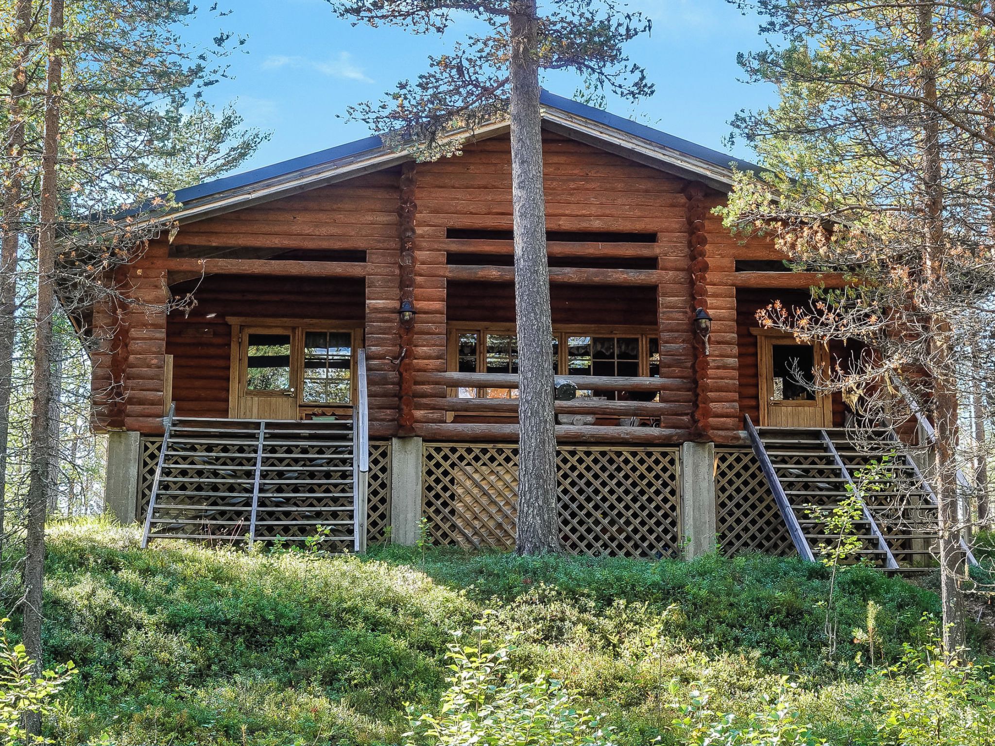 A log cabin with a porch, wooden doors, and a staircase leading up to the entrance.