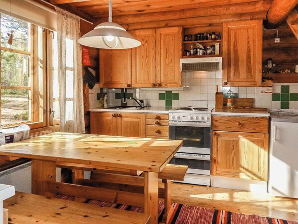 A rustic kitchen with wooden cabinets, a stove, and a dining table.