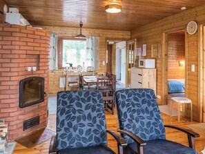 L’intérieur d’un chalet accueillant, avec une cheminée en briques, une table à manger en bois et deux fauteuils à motifs.