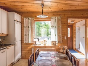 Interno di una baita in legno con angolo cottura, zona pranzo e finestra con tende.