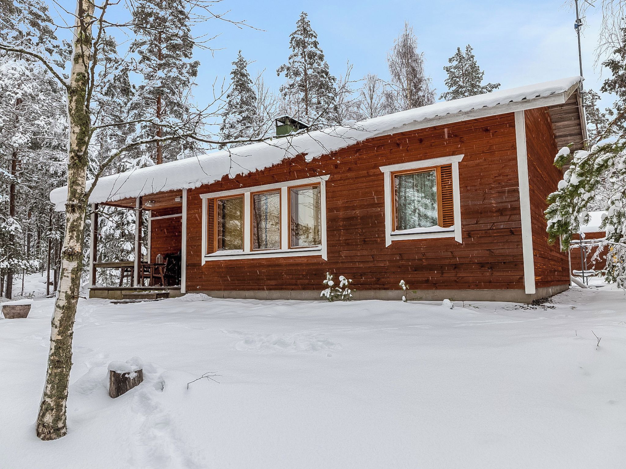 Een houten chalet met een sneeuwbedekte dak, omringd door bomen.
