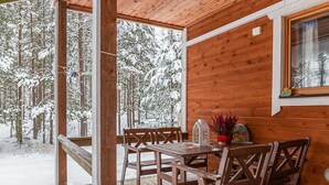 Een houten chalet met een houten terras en een tafel met stoelen.