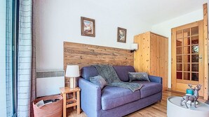 Una sala de estar acogedora con un sofá azul, cabecero de madera y una mesita de noche con lámpara.
