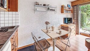 Una cocina moderna con comedor, armarios de madera, salpicadero azulejado y un amplio ventanal con vistas a zonas verdes.