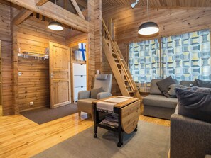 Ein Blockhaushaus-Interieur mit einer Holztreppe, einem Sofa, einem Sessel und einem kleinen Tisch mit Zeitschriften.