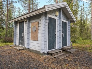 Une petite cabane avec un toit en pente, deux portes et un jeu de fléchettes fixé au mur.