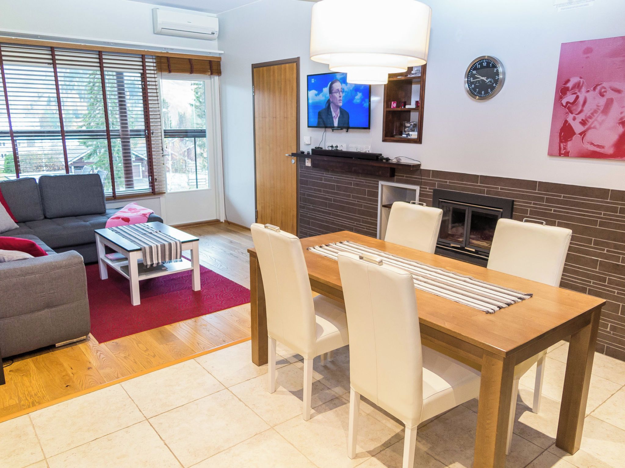 A modern living room with a dining area, a fireplace, and a television.