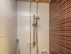 Une douche équipée d’un pommeau de douche à main et d’un robinet fixé au mur.