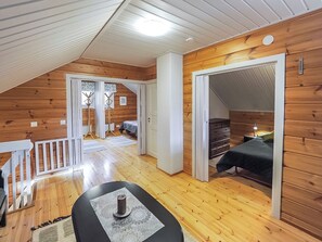 A wooden interior with a staircase, a bed, and a table with a candle. - Kiela 2 by Interhome (Kittilä)