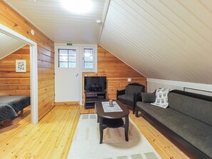 A cozy room with wooden walls, a sofa, a TV, and a small table.