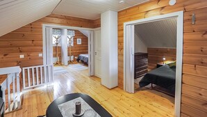 Un dormitorio acogedor en el ático con paredes de madera, un techo inclinado y una pequeña mesa con una vela.