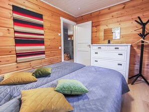 A bedroom with a bed, pillows, a dresser, a mirror, and a coat rack. - Kiela 2 by Interhome (Kittilä)