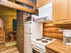 Une cuisine compacte équipée d’un réfrigérateur, d’un four à micro-ondes, d’une cuisinière et d’une machine à café.