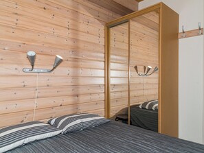 Una camera da letto con parete in listelli di legno, un letto con biancheria a righe e un mobile contenitore con specchio.