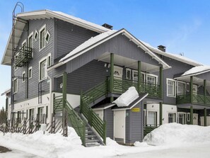 A multi-story hotel with a covered outdoor area, a staircase, and a snow-covered ground.