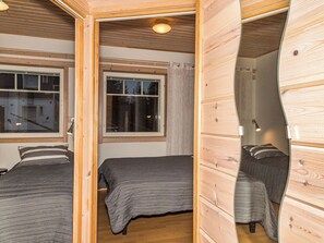 Habitación pequeña con dos camas, una ventana y un muro de madera.