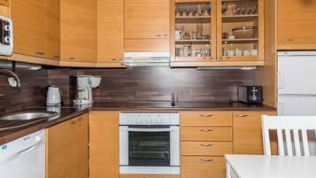 Una cucina compatta con mobili in legno, forno integrato, macchina del caffè e frigorifero.