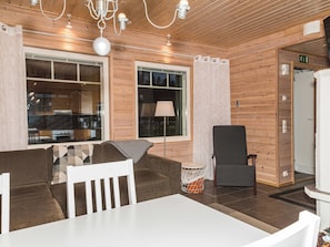 Un intérieur moderne avec un mur en bois, un coin repas doté d’une table blanche et un fauteuil gris.