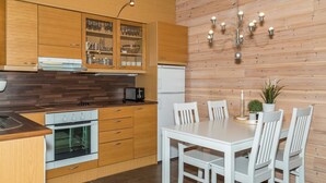 Una cocina moderna con armarios de madera, una mesa de comedor blanca y una araña.