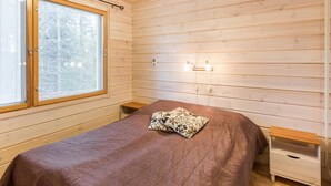 Un dormitorio acogedor con una cama de madera, una ventana con persianas, una mesita de noche y una mesilla.
