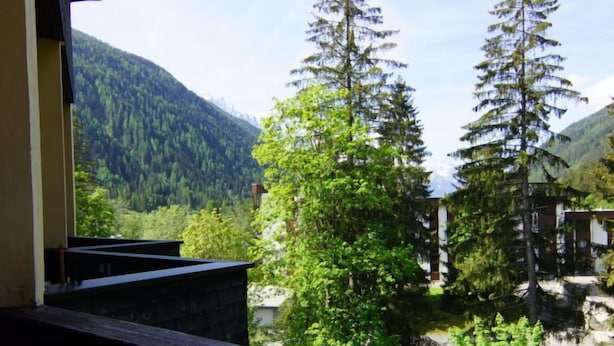 A view from a balcony overlooking a mountainous landscape with dense forests and a clear sky. - Grand Roc by Interhome (Argentière)