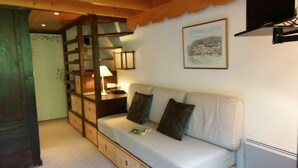 A cozy room with a wooden bunk bed, a white sofa with cushions, a lamp, and a framed picture on the wall. - Grand Roc by Interhome (Argentière)