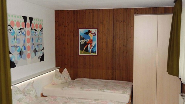 Ein Schlafzimmer mit zwei Betten, einem Holzschrank und einem Poster an der Wand.