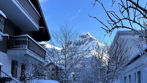 Eine verschneite Straße mit Gebäuden und einem Berg im Hintergrund.