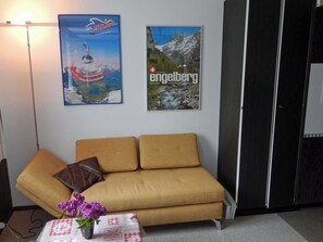 A room with a sofa, a small table with a vase of flowers, and two posters on the wall. - Sörenweg 4 Appartement/Fewo 2-Bettwohnung by Interhome (Engelberg)