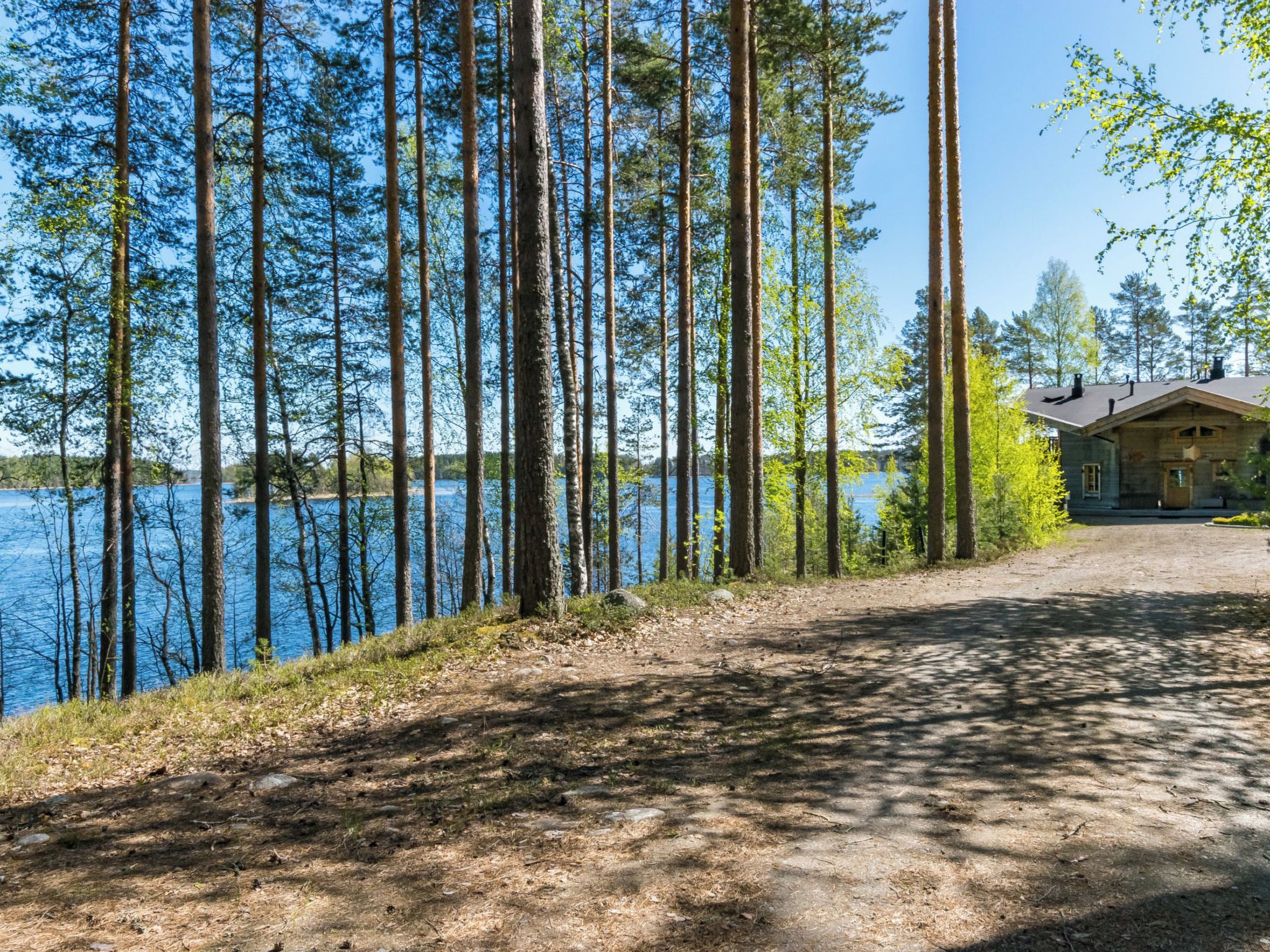Une cabane au bord d’un lac, accessible par un sentier de terre.