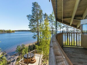 A wooden deck with a hot tub and a view of a lake. - Villa pyöriäinen by Interhome (Kerimäki)
