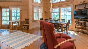 A wooden cabin interior with a dining area, a TV, and large windows. - Villa pyöriäinen by Interhome (Kerimäki)